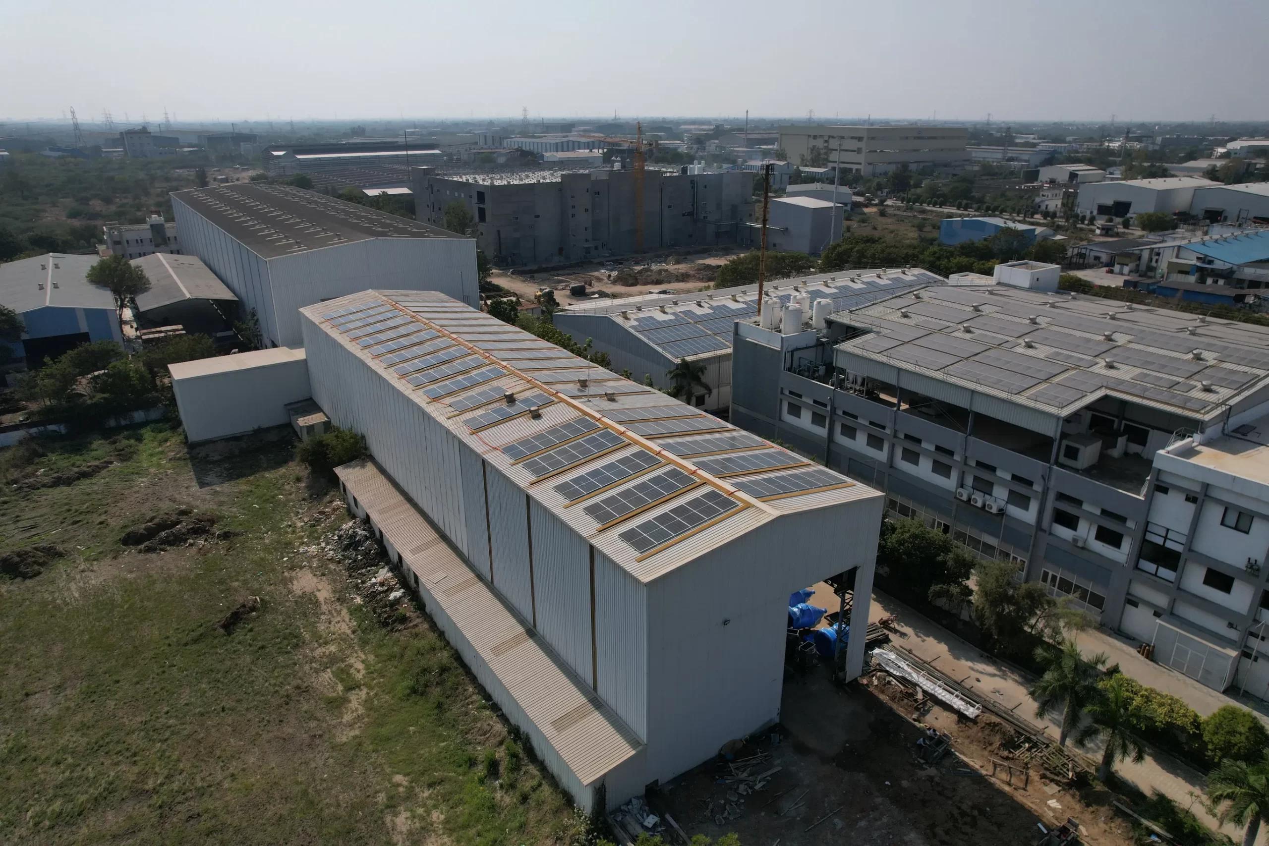 White industrial warehouse with long rows of rooftop solar panels